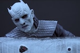 The Night King peers over an ice wall.