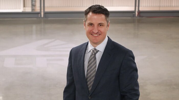 President of Canadian firm Tilray, Brendan Kennedy, standing in a big empty warehouse.