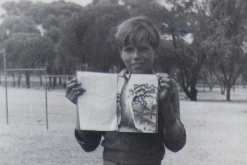 An Aboriginal teenager holds a drawing