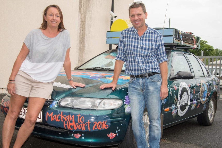 Nicole Dawes and Peter Crabbe lean on the bonnet of the 1998 Ford Falcon they will drive from Cairns to Hobart.