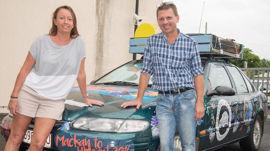 Nicole Dawes and Peter Crabbe lean on the bonnet of the 1998 Ford Falcon they will drive from Cairns to Hobart.