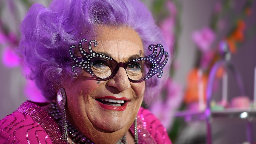 A close up of Dame Edna complete with her iconic sunglasses and purple hair.