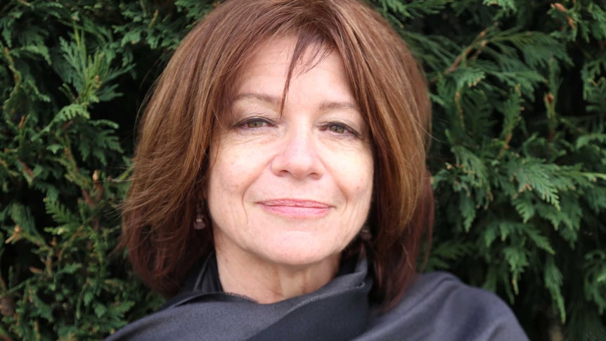 ARIA-award winning performer Jenny Morris stands in front of a bush.