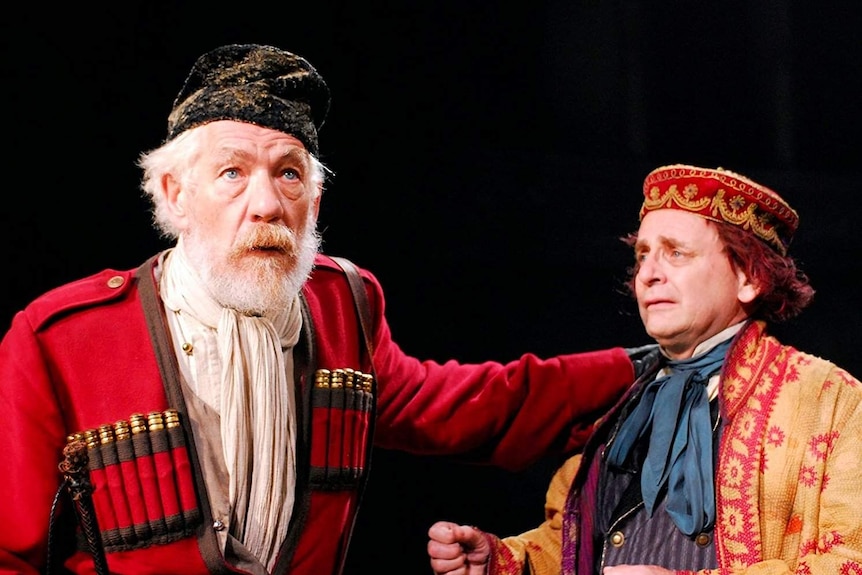 An older man looks pained, a younger man looks to him, two actors in the film version of the Shakespeare play King Lear.