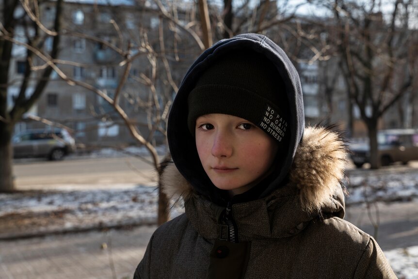 a young girl with a hood with fake fur, looks impassive