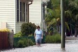 A woman wades through floodwaters in NSW.