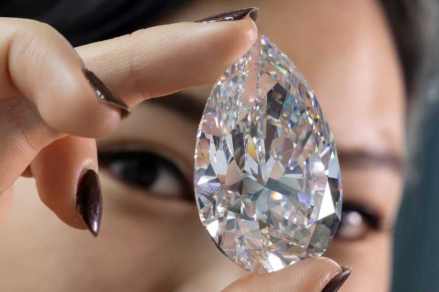 Hand holds a large diamond. 