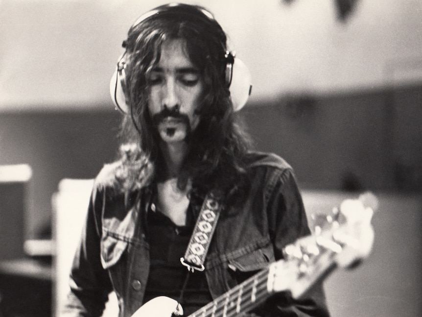 Photographic portrait of Alan Escombe playing bass guitar in the Island Recording Studio, 1971.