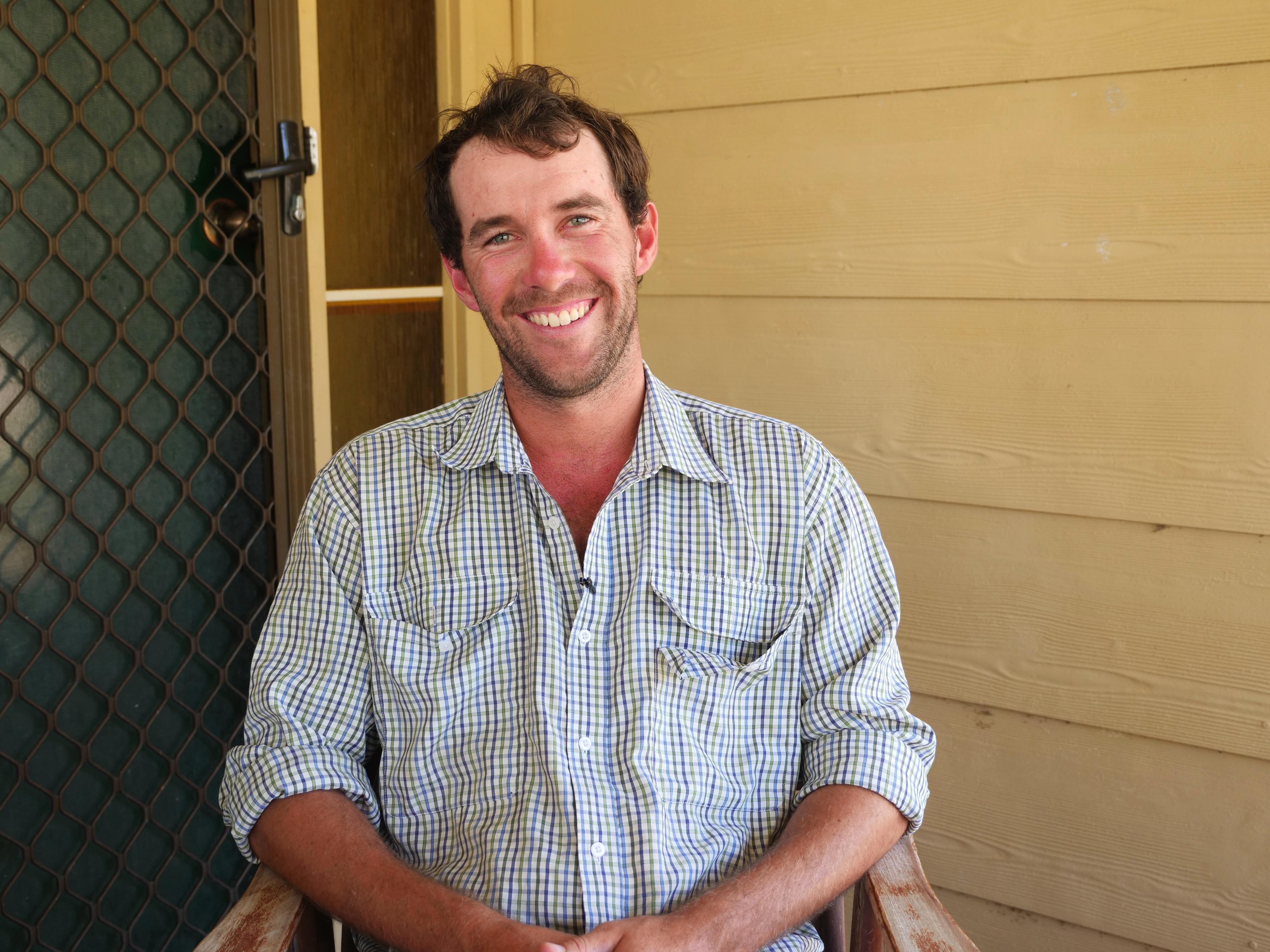 Wilson sentado em uma cadeira sorrindo para a câmera. 