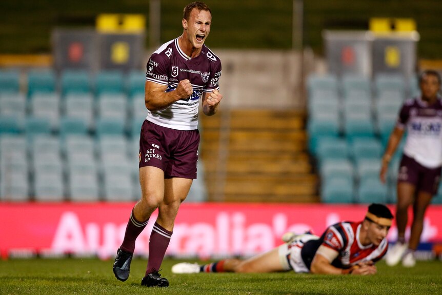 A Manly NRL player screams out and pumps his fists as he celebrates kicking the winning field goal against the Sydney Roosters.