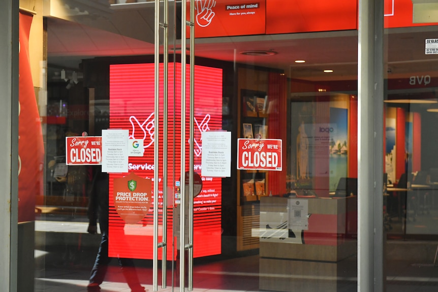 a closed travel agency displays closed signs on its doors