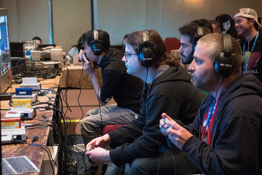 The people playing videogames sit in front of televisions