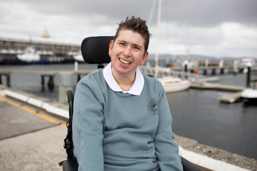 Janelle McMillan smiles at the camera with the Hobart waterfront behind her.