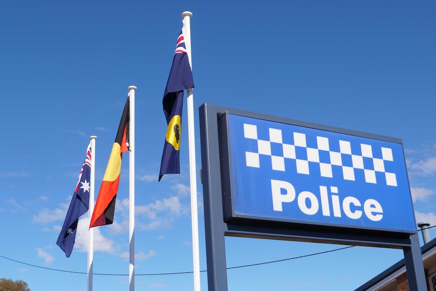 The Australian flag, the Aboriginal flag and the WA State flag flying outside a police station in Norseman.