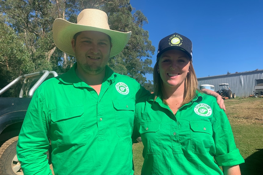 A man and woman in bright green shirts smile at the camera with their arms around each other.