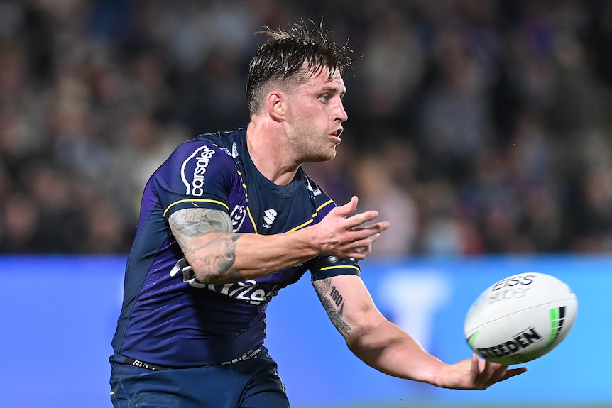 A Melbourne Storm NRL player passes the ball to his left against Manly
