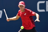 A tennis player eyes the ball as he swings his racquet for a forehand return.