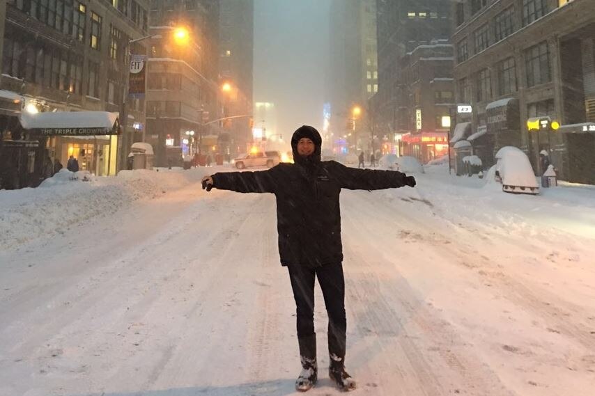 A man standing in cold weather gear and gumboots stands in snow in New York