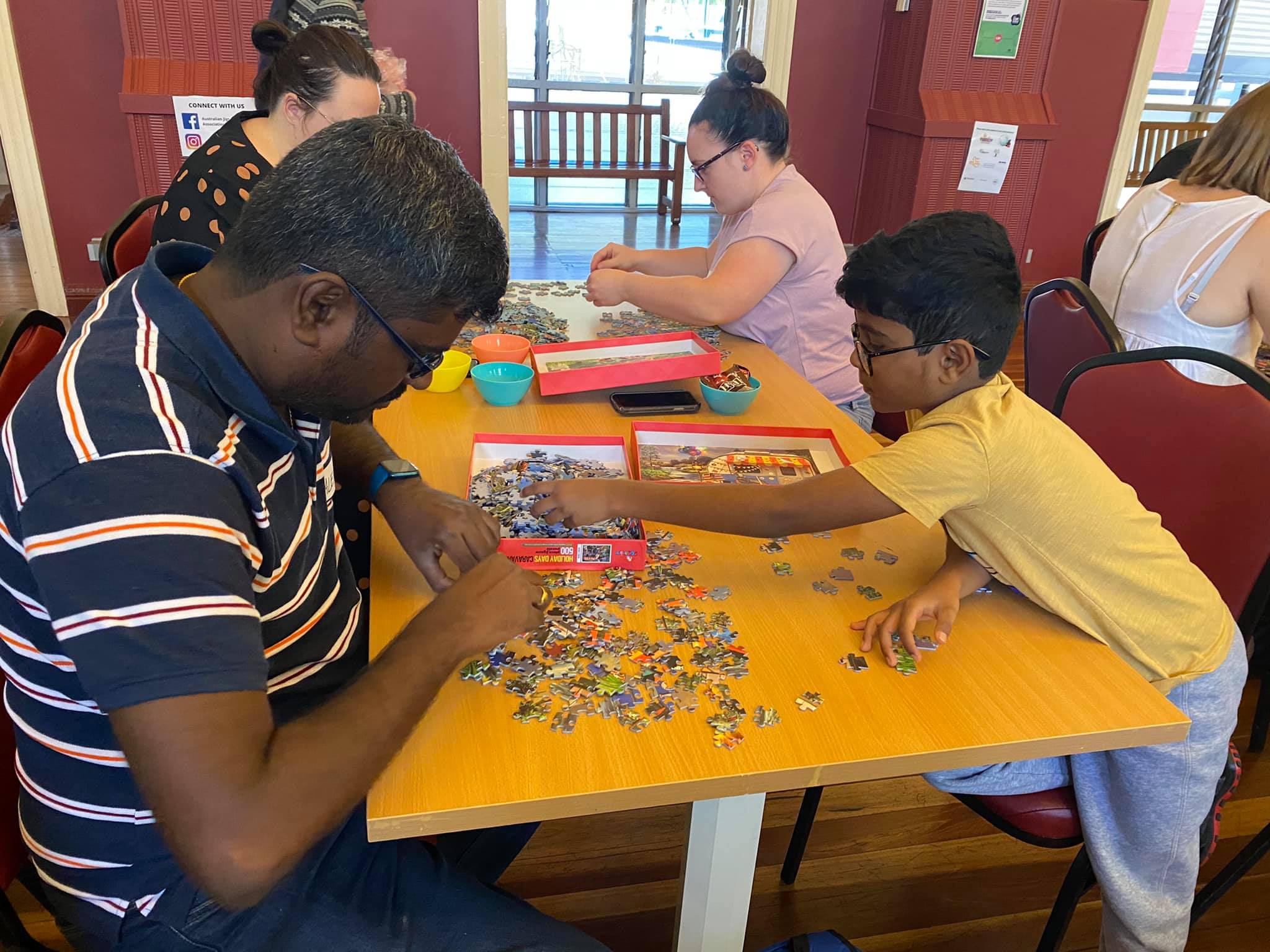 A man and his son sort and do a puzzle on a table as part of a competition
