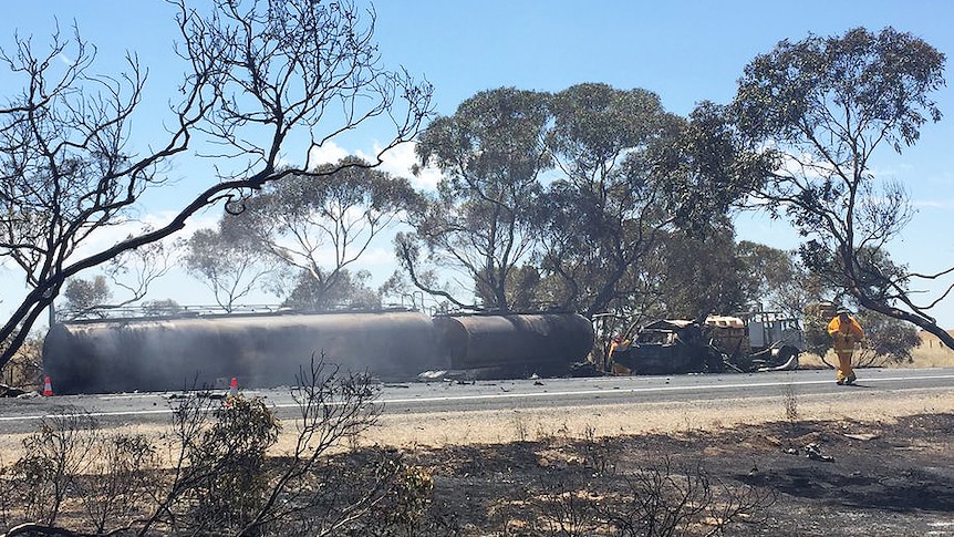 A truck smouldering with smoke lays on its side on the Dukes Highway.