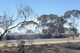 A truck smouldering with smoke lays on its side on the Dukes Highway.