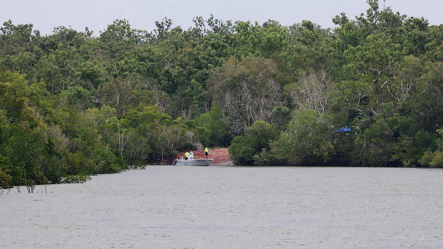 A police boat can be seen launching into the water in between thick bush.