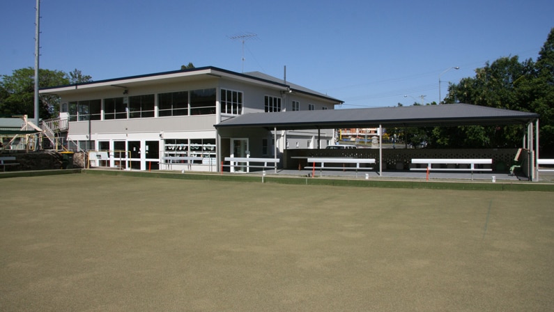 Two storey building with lawn bowl green in front of it.