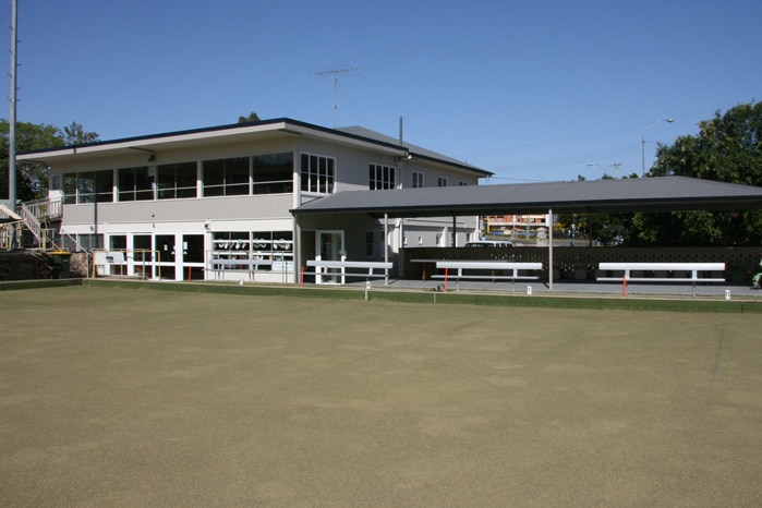 Two storey building with lawn bowl green in front of it.