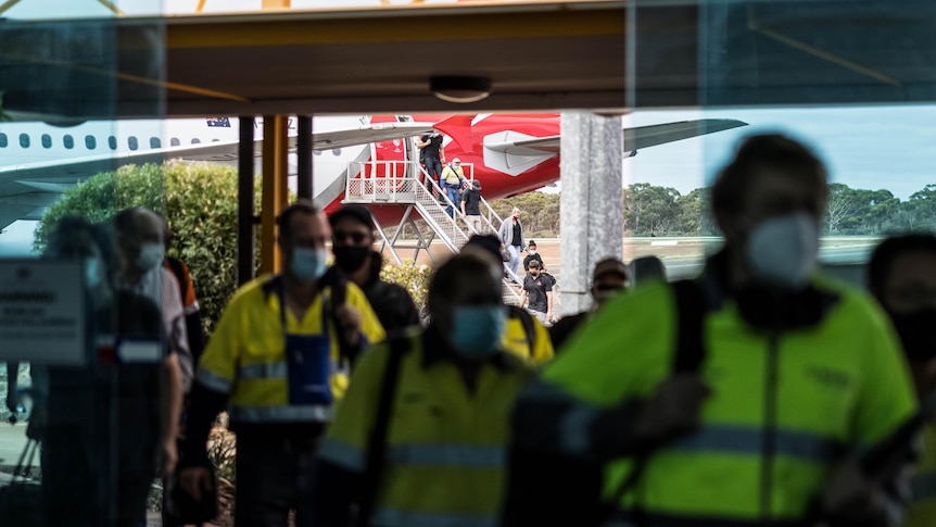 People walking into the airport after arriving on a Qantas jet.  
