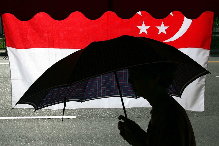 A Singaporean man walks past his country's flag in Singapore