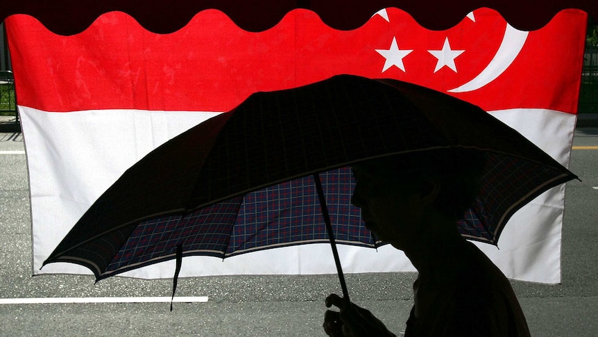 A Singaporean man walks past his country's flag in Singapore
