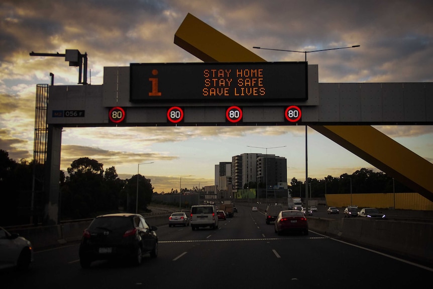 An illuminated sign above a major road that reads "Stay home, stay safe, safe lives".