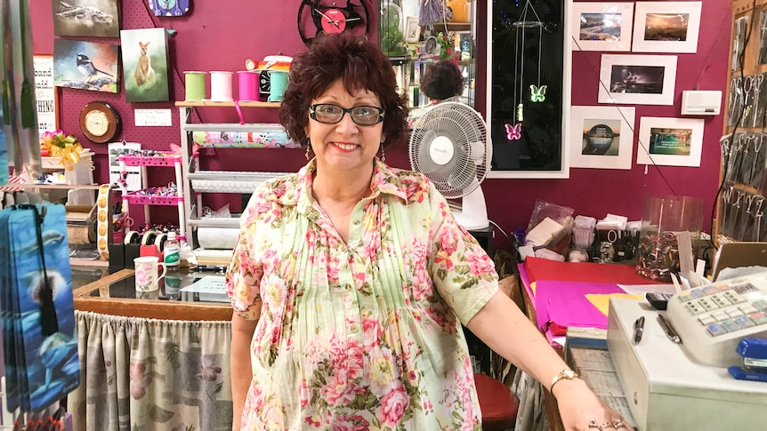 A woman stands in a shop filled with paintings and knick knacks