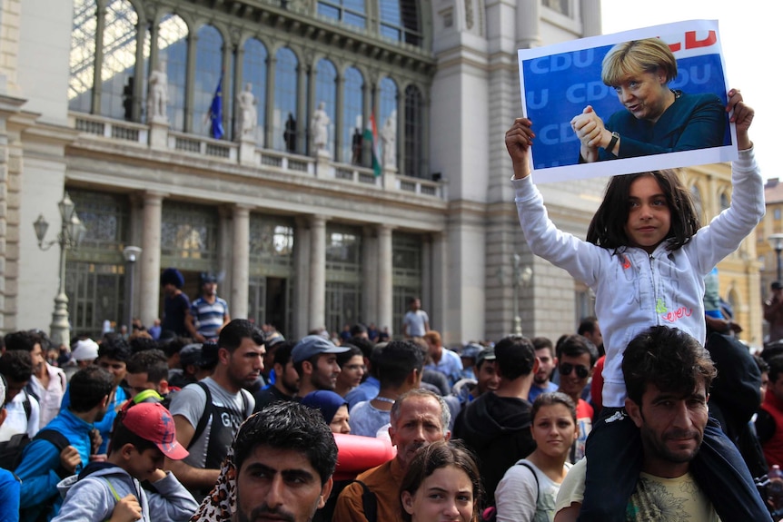 A girl holds up a poster of Angela Merkel.