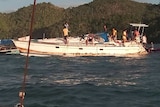 A white yacht, listing, with Philippines sailors aboard.