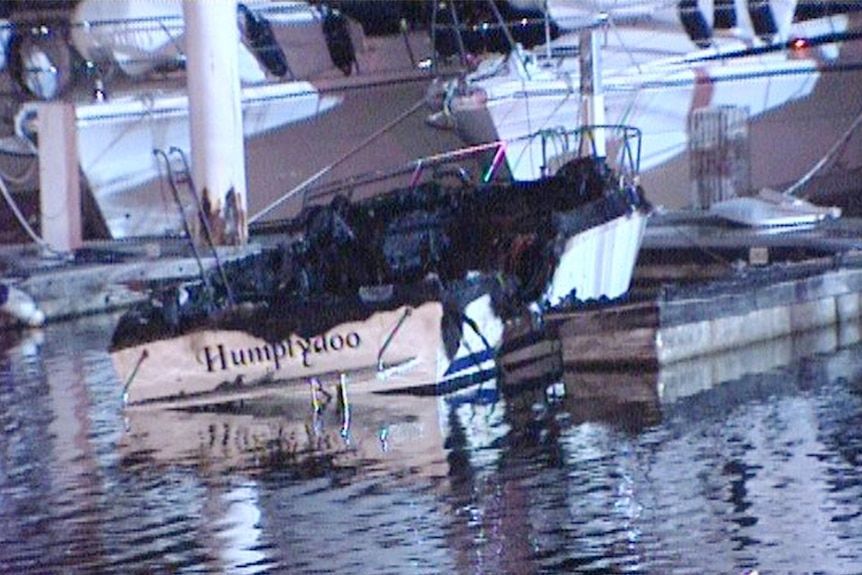 The remains of a boat called Tina sit in the water after the vessel was gutted by fire at Hillarys boat harbour.