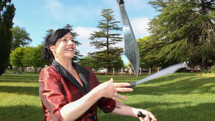 A woman juggling knives in a park