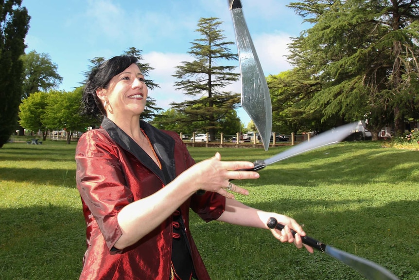 A woman juggling knives in a park