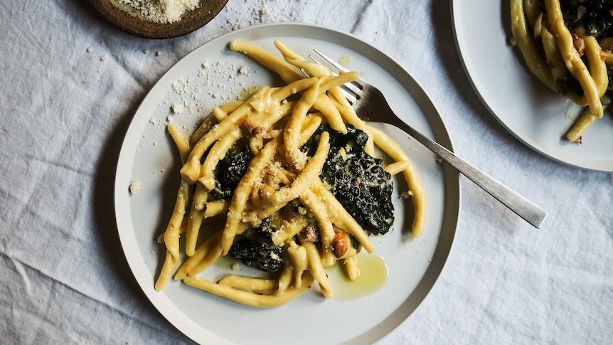 A plate of creamy maccheroni with torn kale, lemon juice, almonds and parmesan, a fast midweek dinner.