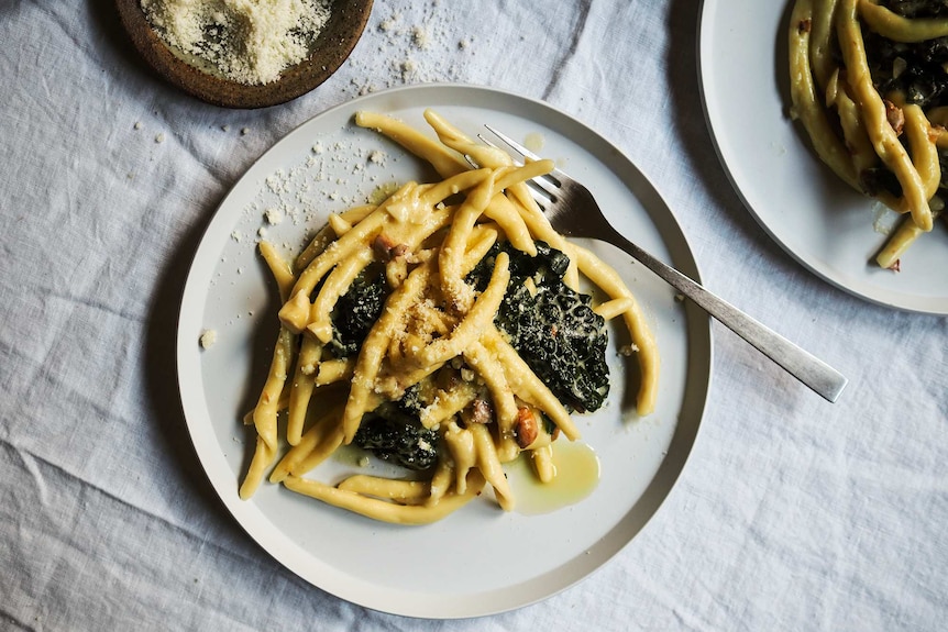 A plate of creamy maccheroni with torn kale, lemon juice, almonds and parmesan, a fast midweek dinner.