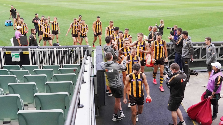 Hawthorn players walk off the MCG and down the race after completing their game against Brisbane.