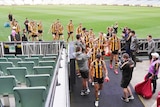 Hawthorn players walk off the MCG and down the race after completing their game against Brisbane.