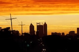 Perth's skyline with a bright orange and yellow sky in the background.