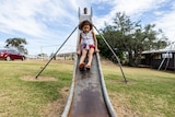 An Aboriginal girl rides a slide