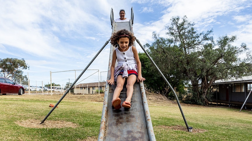 An Aboriginal girl rides a slide