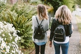 Two teenage girls walk together on a footpath.