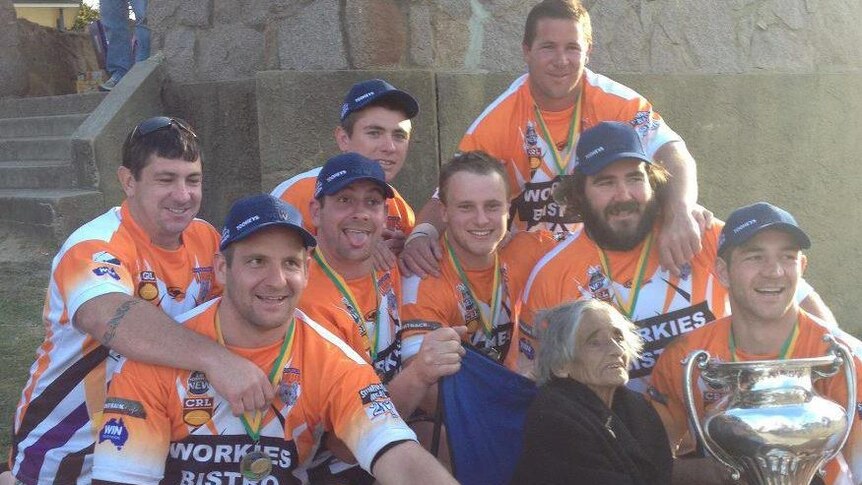 Jeremy Fittler's football team poses with a trophy after winning the grand final