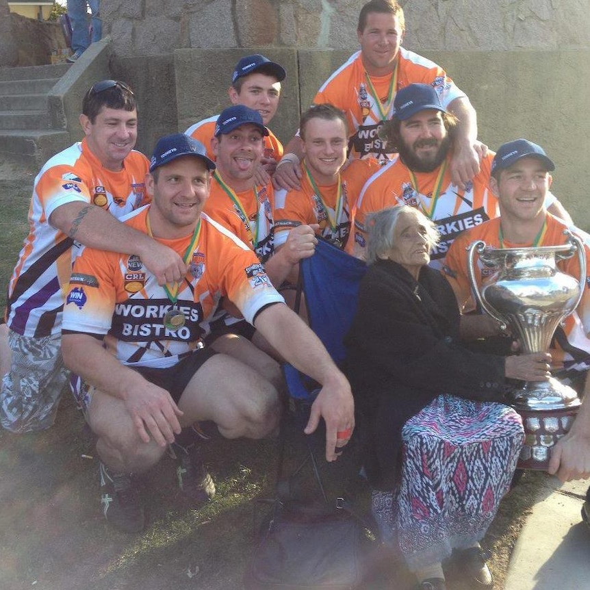 Jeremy Fittler's football team poses with a trophy after winning the grand final