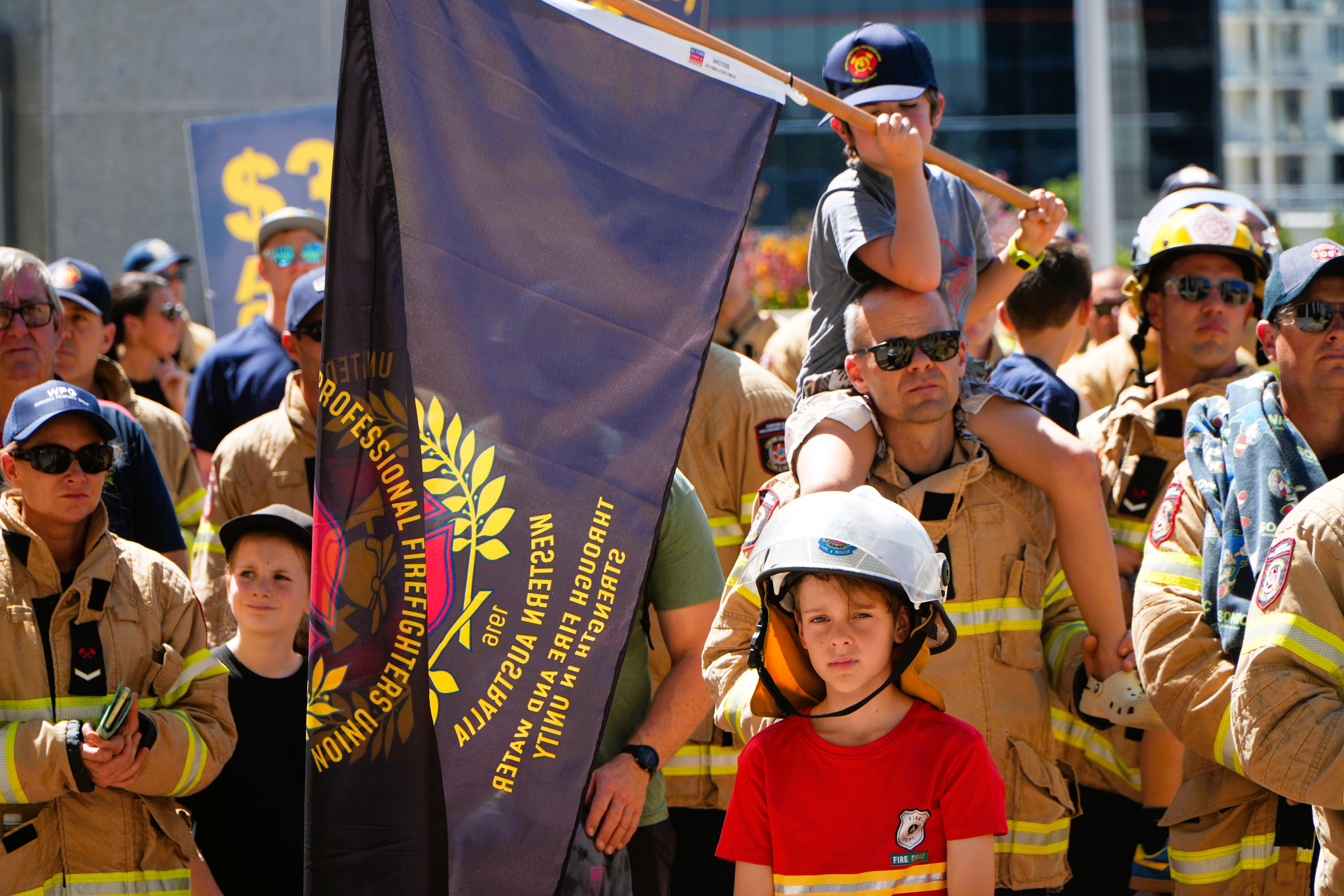 Un grupo de bomberos y sus hijos protestan en un mitin en Perth.