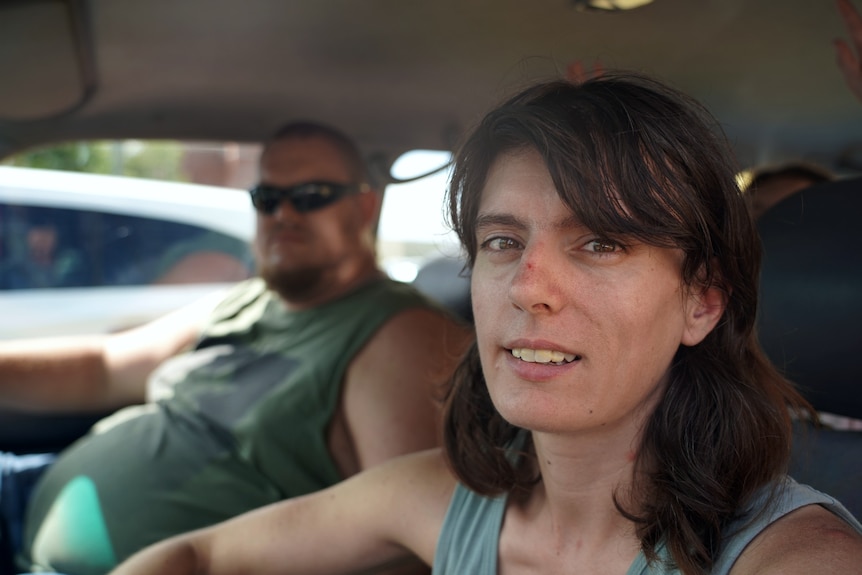 a man and woman sit in the front seat of their car